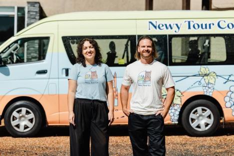 Two people standing in front of a tour van.