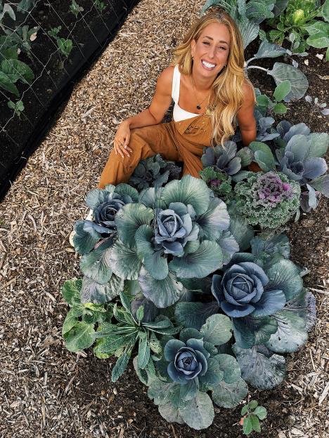 Woman sitting in garden amongst homegrown brassicas.