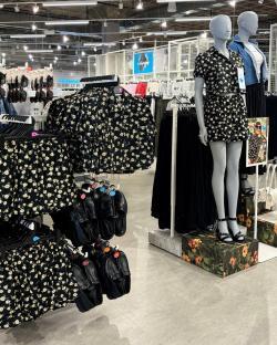 Primark summer clothing display with floral print shorts and tops, and shoes.