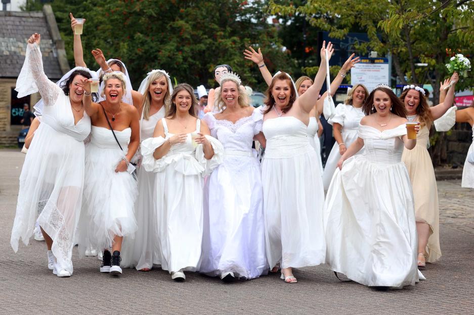 Group of women in white dresses and veils participating in a pub crawl.