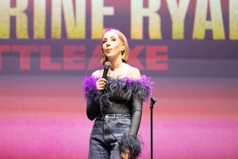 Katherine Ryan performing on stage with a microphone.