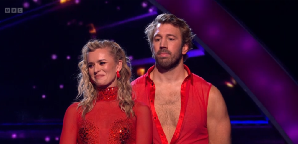 Two dancers in red outfits on a stage.