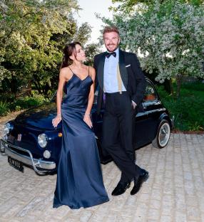 David and Victoria Beckham posing by a classic car.