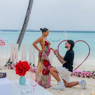 Beach proposal; a man kneeling to propose to a pregnant woman.
