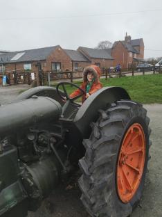 Boy driving a vintage tractor.