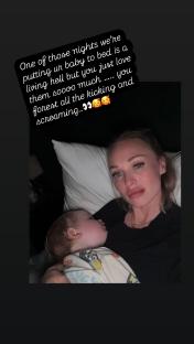 Woman holding sleeping baby in bed.
