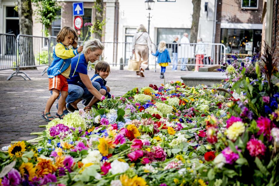 A woman and two children placing flowers at a memorial.
