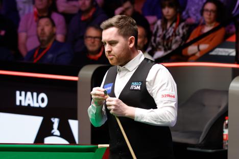 Jak Jones chalking his cue at a snooker match.