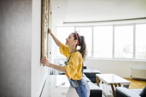 Woman hanging a picture on a wall.