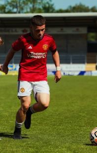 Soccer player in Manchester United uniform running on the field.