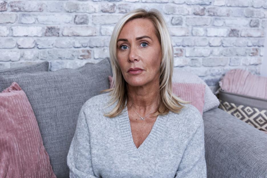 Woman sitting on a couch, looking at the camera.