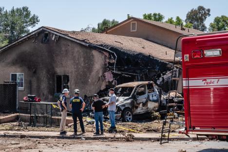NTSB and FAA investigators at the site of a plane crash that damaged a home and vehicle.