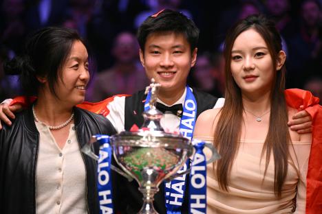 Zhao Xintong with trophy and companions after winning the World Snooker Championship.