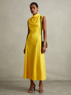 Woman in a yellow midi dress and brown heels.