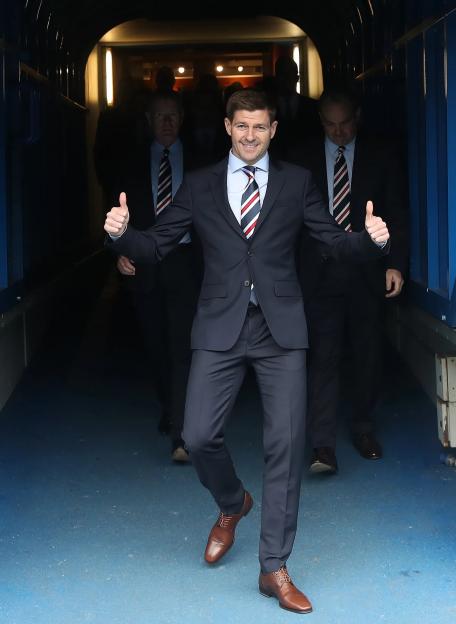 Steven Gerrard in a suit giving two thumbs up, being unveiled as the new manager of Rangers Football Club.