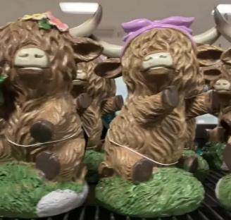 Highland cow garden ornaments on a store shelf.