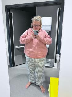 Woman in pajamas using a smartphone in a restroom.