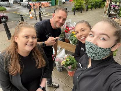 Group photo of four people with flowers.