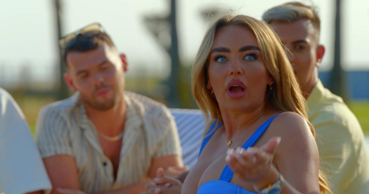 Screenshot of a woman in a blue swimsuit reacting dramatically while two men sit behind her.