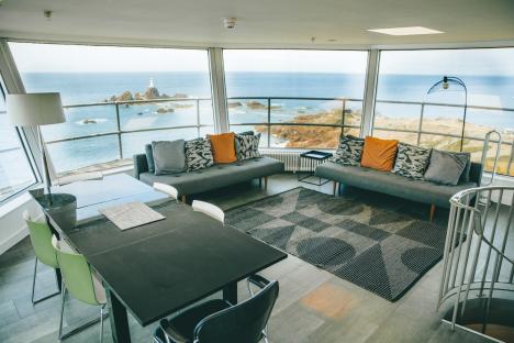 Ocean view living room with couches and dining table.
