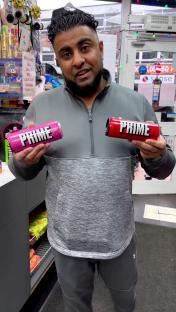 Man holding pink and red Prime energy drink cans.