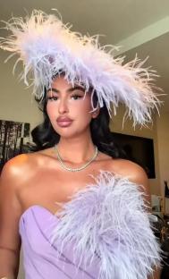 Woman in lavender feather hat and dress.