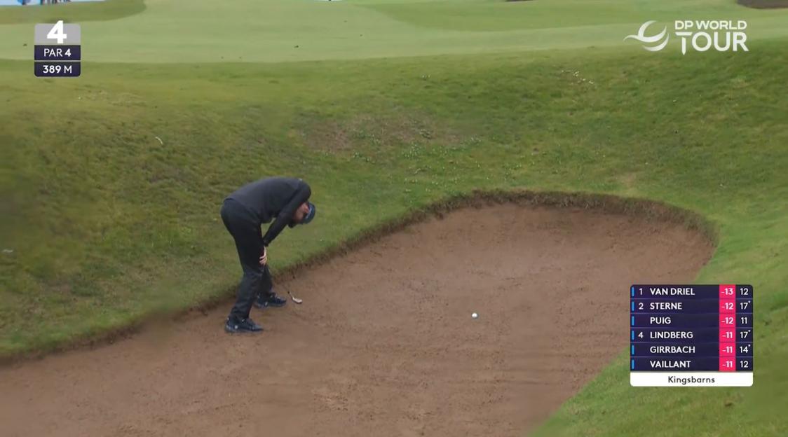 A golfer in a sand trap on a course with a scoreboard displaying tournament leaders.