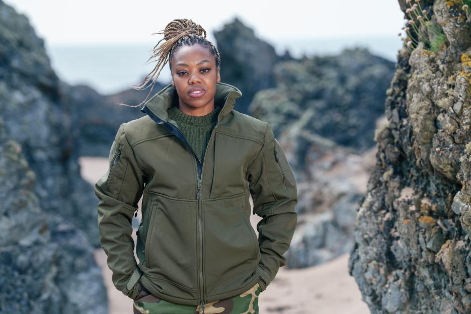 Lady Leshurr standing on a beach.