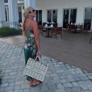 Woman in floral dress carrying a large tote bag.