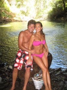 Couple sitting on a rock by a waterfall.