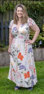 Woman in floral maxi dress standing in a garden.