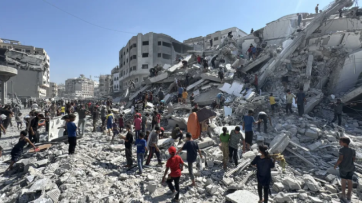 People walk through the rubble of destroyed buildings.