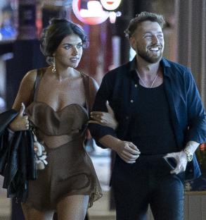 Sam Thompson and Samie Elishi arm in arm at a party.