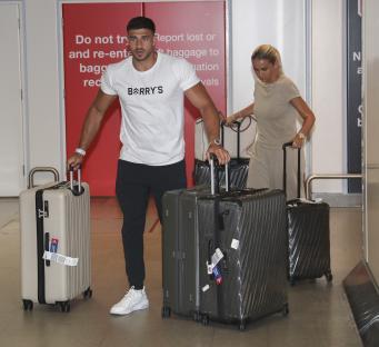 Molly Mae and Tommy Fury arriving at an airport with luggage.