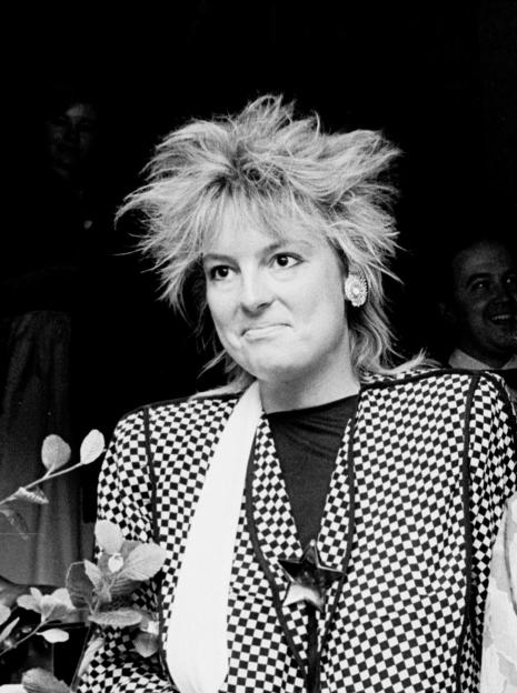 Olivia Channon in a checkered jacket and an earring, with spiky hair.