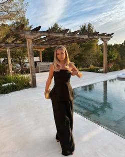 Woman in black jumpsuit by a pool.