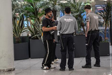 Homeless person at an airport speaking with security guards.