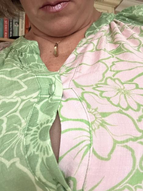 Close-up of a woman's chest wearing a pink and green floral blouse.
