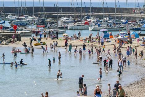 Sunbathers enjoying a hot day at Lyme Regis beach in Dorset, UK.