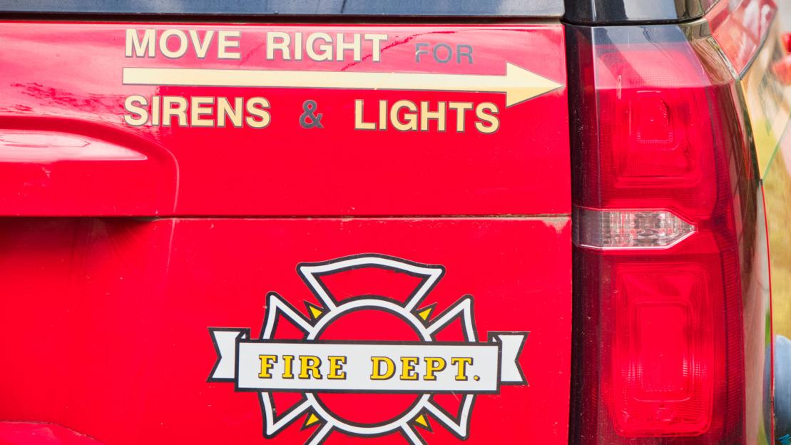 Red fire department vehicle's rear with "Move right for sirens & lights" and fire department logo.
