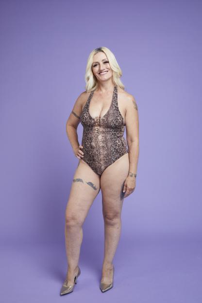 Photo of a smiling woman in a snakeskin swimsuit.