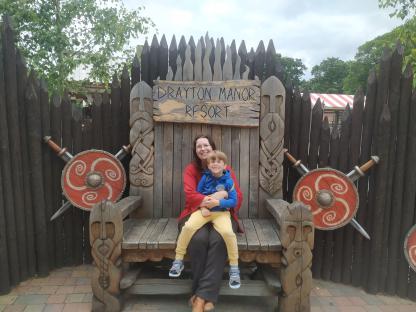 Woman and child sitting on a large wooden throne at Drayton Manor Resort.