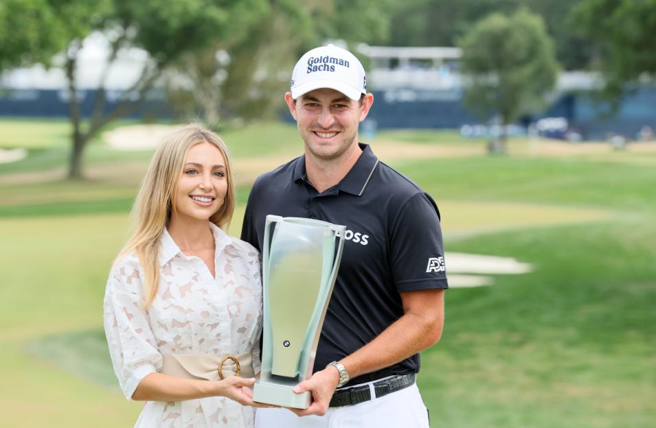 Patrick Cantlay and his wife Nikki Guidish posing with the BMW Championship trophy.