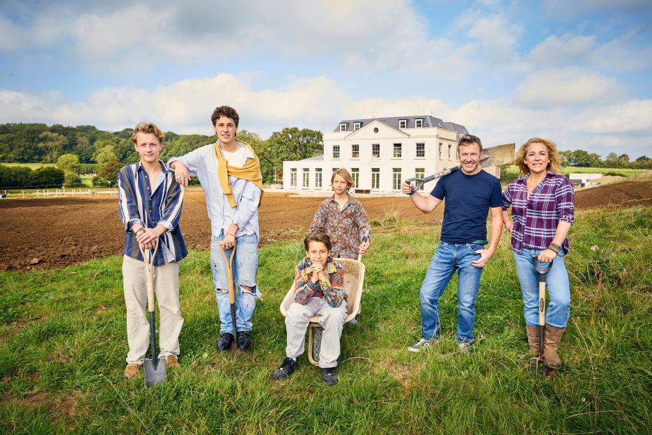 The Beeny family stands in front of their large house under construction.