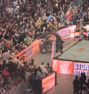 Stone Cold Steve Austin driving an ATV in a wrestling arena.