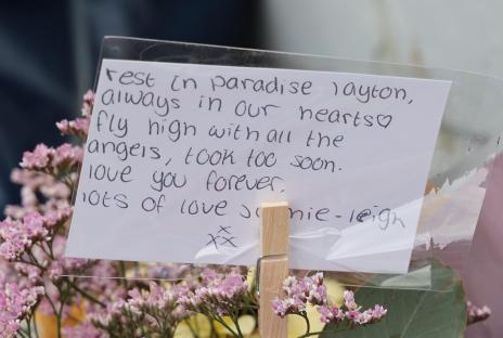 Handwritten tribute attached to flowers: