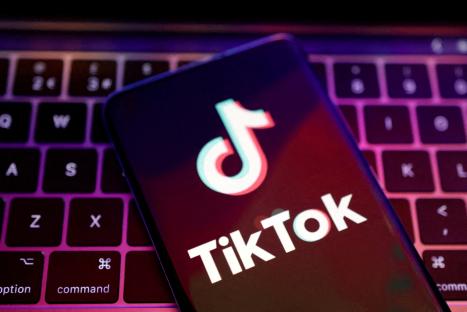 Illustration of the TikTok logo on a smartphone screen above a laptop keyboard.