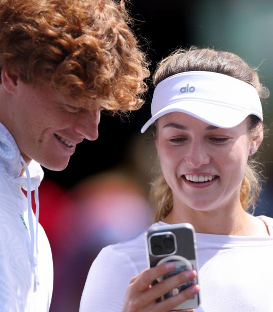 Jannik Sinner and Anna Kalinskaya looking at a smartphone.