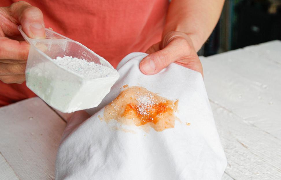Removing a tomato stain from white fabric with detergent.