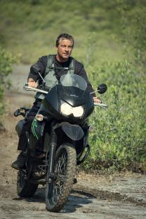 Man riding a motorcycle on a dirt road.